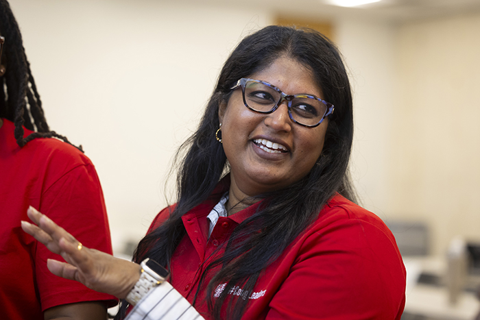 Woman with black hair and glasses in class waving her hand